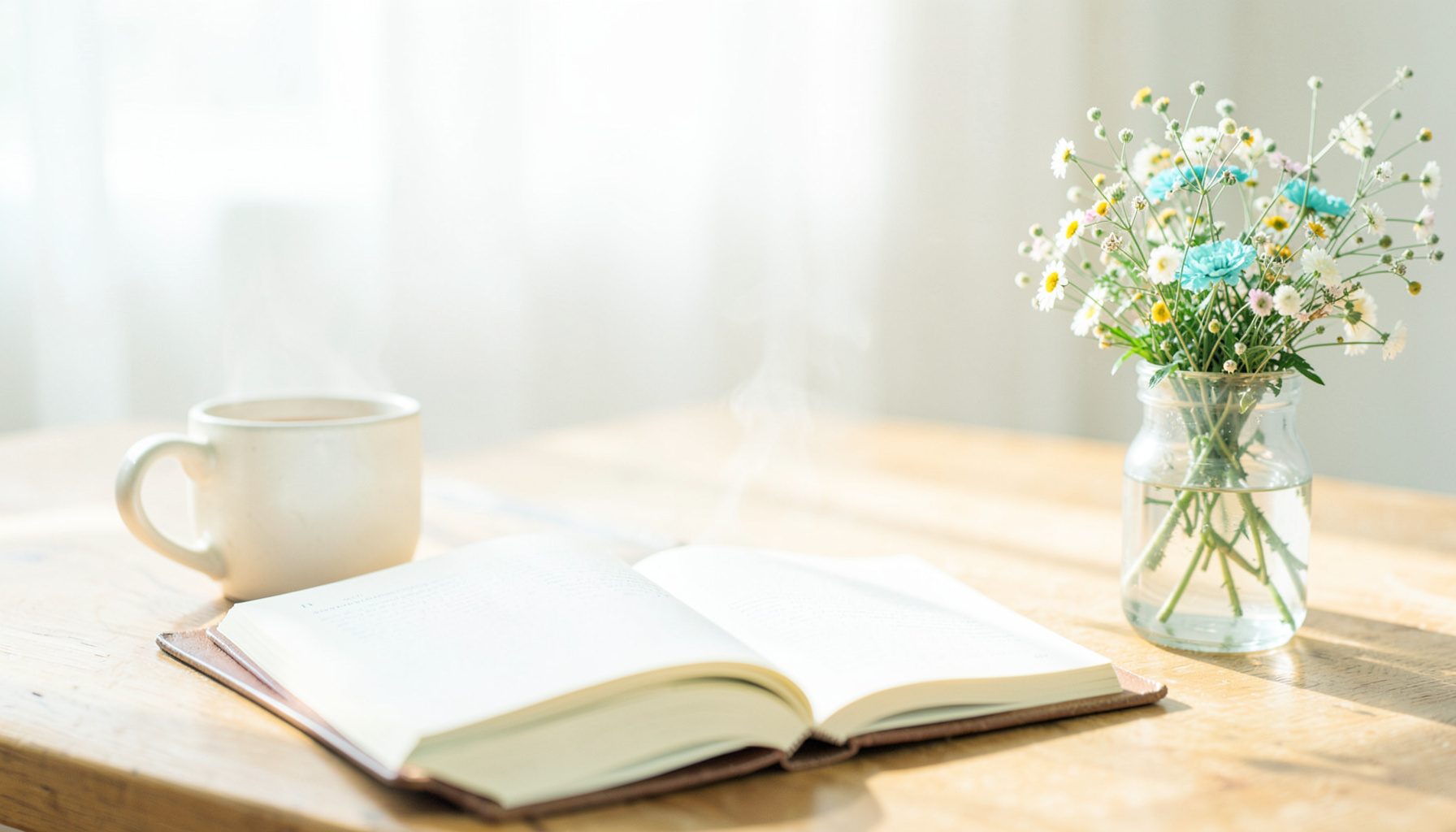 A bright, airy photograph of a sunlit wooden desk with an open journal, a steaming mug, and a small vase of wildflowers, conveying warmth and quiet reflection.